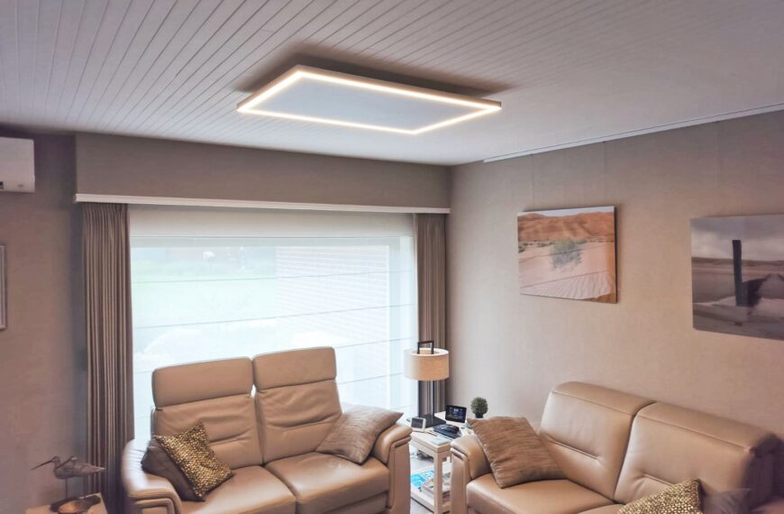 Groot infraroodpaneel met warme LED-verlichting aan het plafond van een zithoek met leren zetels