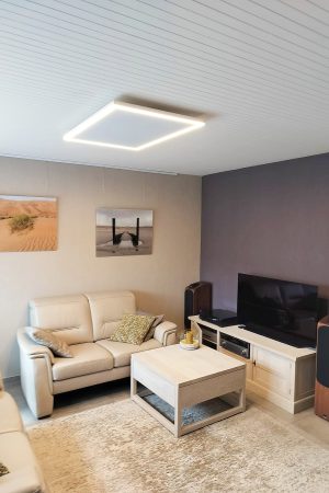Infraroodpaneel met warme LED-verlichting aan het plafond van een woonkamer met tv-hoek