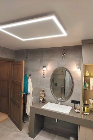 Infraroodpaneel met LED-verlichting aan het plafond van een badkamer met grijze tegels