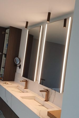 Twee infraroodspiegels met verticale LED-verlichting boven een dubbele wastafel in een luxueuze badkamer